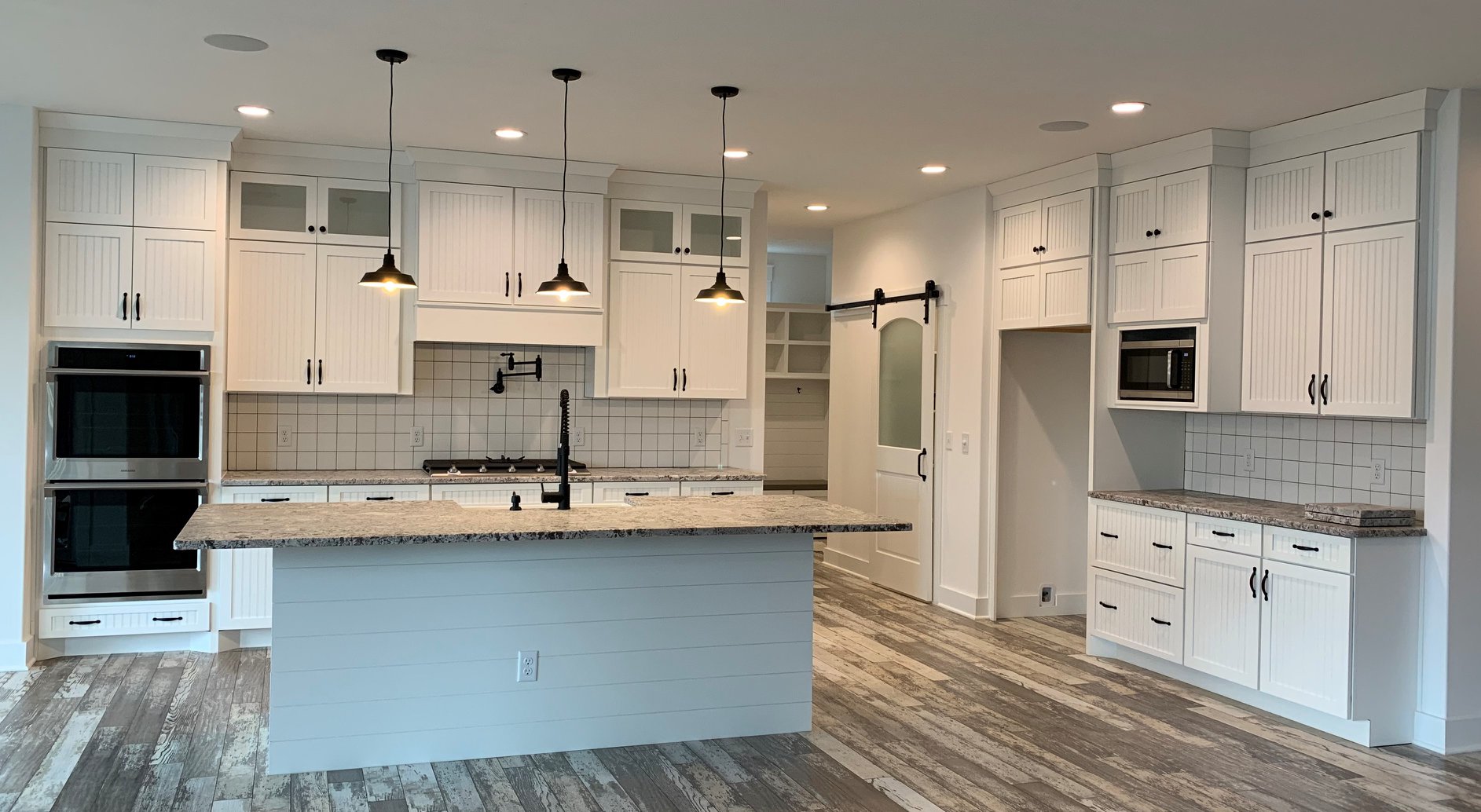 Modern remodeled kitchen with marble waterfall island and brass pendants